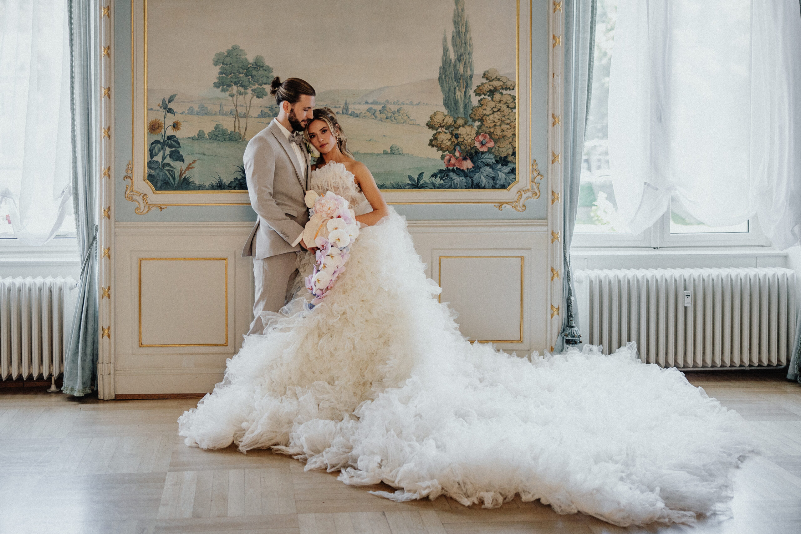 Brautpaar vor Wandmalerei im Blauen Salon Alleesaal Bad Schwalbach - Traumkleid aus Tüll von Millia London - Brautstrauß elegant und pastellfarben mit Orchideen - Anzug Bräutigam von Men's Couture Ingelheim am Rhein - romantische Prinzessinhochzeit - modern day princess wedding - Romantik pur für die Hochzeit - moderne Sissi-Hochzeit wie im Märchen - Märchenhochzeit - Träume die wahr werden - kleine Luxushochzeit - wir feiern im engsten Kreis - Microwedding - kleine Hochzeit mit Stil und Klasse - Hochzeit ohne Abstriche - kein Stress mit der Hochzeitsplanung dank Hochzeitsplanerin Pia Schmeling - MichelleMarie Weddings - Frankfurt-Wiesbaden-Mainz-Taunus-Hessen-deutschlandweit - Schlosshochzeit - Hochzeit mit Schloss-Charakter - royal heiraten - Royale Hochzeit im kleinen Kreis - maßgeschneiderte Hochzeit mit Highlights die in Erinnerung bleiben - Hochzeiten die neue Maßstäbe setzen - Wedding Design das alle Augen zum strahlen bringt - Momente fürs Leben - First Look traumhaft schön - Blumen Koser Hochzeitsfloristik - Hochzeitsfotografie Rina Radtke Photography